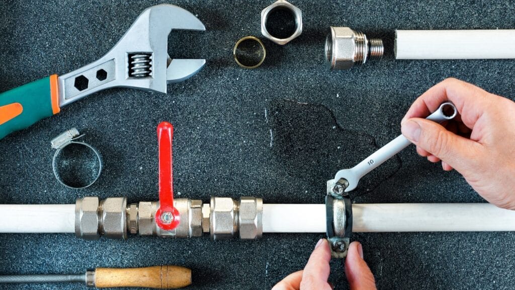 Plumber repairing a pipe valve with an adjustable wrench in Newnan