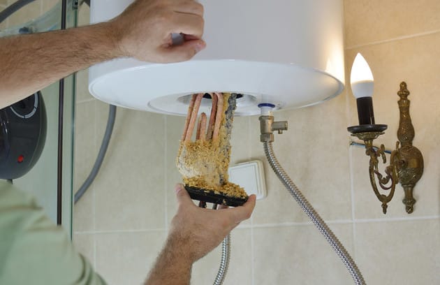 Technician removing mineral buildup from a water heater in Newnan