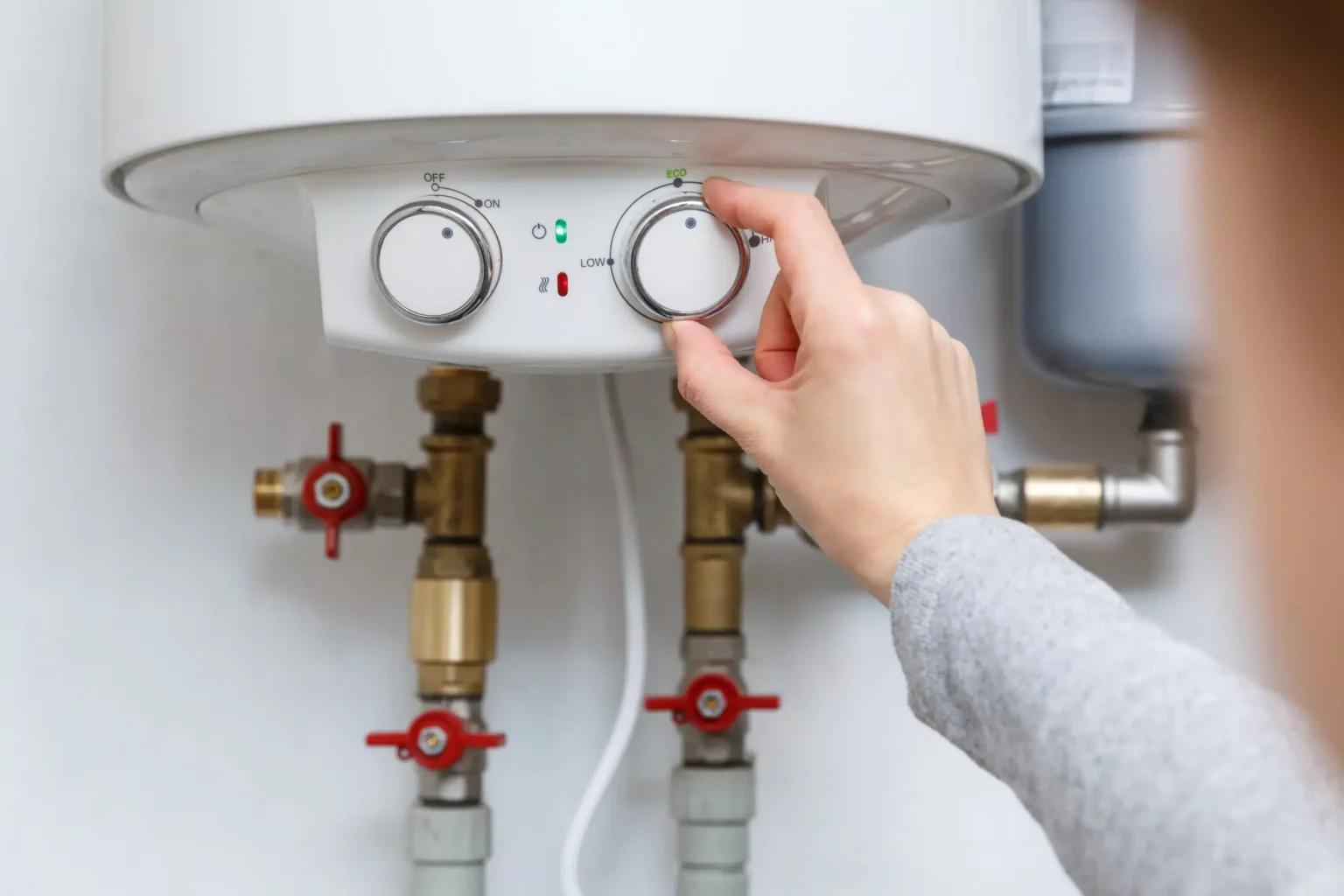 Homeowner adjusting the temperature controls on a water heater in Newnan